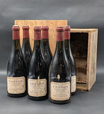 quatre bouteilles de vin rouge dans un coffret en bois posé sur une table