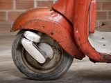 a red scooter that is parked in front of a brick wall