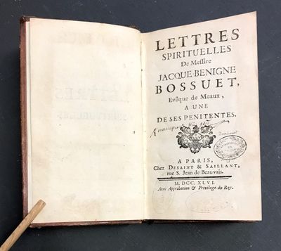 un livre ouvert posé sur une table, à côté d'un bâton en bois
