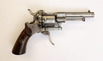 un vieux revolver avec une poignée en bois sur une surface blanche
