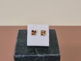 a pair of gold earrings sitting on top of a marble block