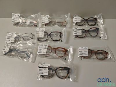 several pairs of eyeglasses are in plastic bags on a table
