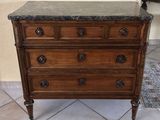 a wooden chest of drawers with marble top on a tile floor