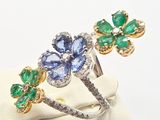 two rings with blue and green stones are sitting on a white cloth
