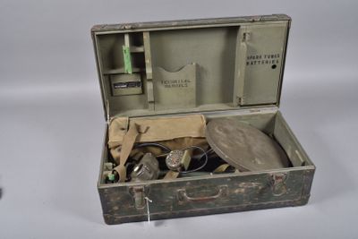 une vieille valise contenant des outils, posée sur une surface blanche