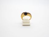 a gold ring with a black stone sits on a white surface