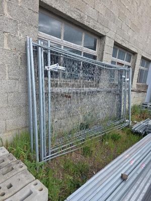 une clôture située à côté d'un bâtiment où se trouvent de nombreux tuyaux