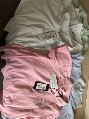 a pile of clothes and a cell phone on a bed