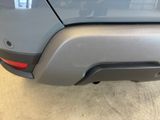the rear end of a gray car with a red tail light