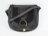 a black leather cross body bag with a metal ring on the front