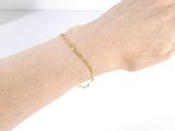 someone is wearing a bracelet with a gold chain on their wrist
