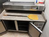 un comptoir sur lequel se trouvent un four à pizza et une pelle à pizza
