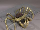 a glass table with a gold spider on it