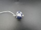 un gros plan d'une bague ornée d'une pierre bleue sur un fond noir