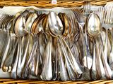 des cuillères et des couteaux à cuillère dans un panier en osier posé sur une table