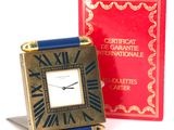 a small clock sitting next to a red book