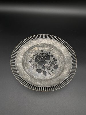 un plat ancien en argent orné de fleurs et de feuilles