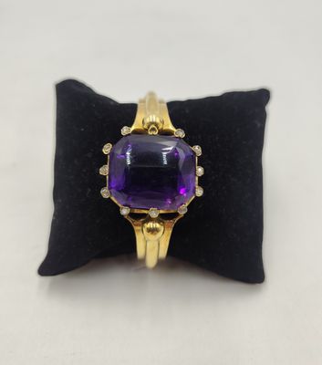 un gros plan d'une bague sertie d'une pierre violette, posée sur un coussin noir