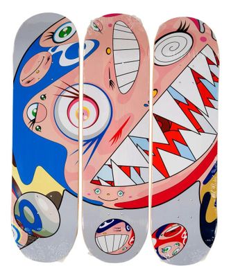 Trois skateboards aux motifs différents sont alignés sur une surface blanche