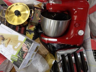 un mixeur rouge posé sur une pile d'ustensiles de cuisine