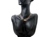 black mannequin head with gold necklace and earrings on a white background
