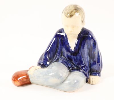 a figurine of a boy sitting on the ground