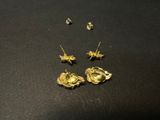 gold plated flower earrings and studs on a black surface