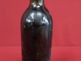 a black bottle with a pink top on a red surface