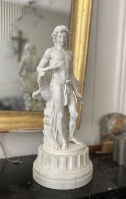 une statue représentant une femme tenant un chien sur une table