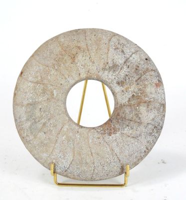 a stone sculpture of a circular object on a stand