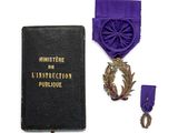 un ruban violet et une médaille sur un livre noir entouré d'un ruban violet
