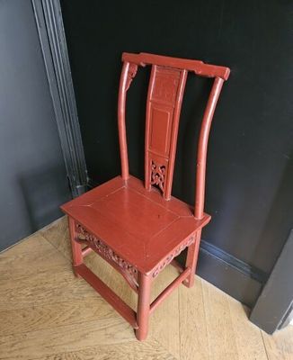 une chaise rouge posée sur un parquet, devant un mur noir