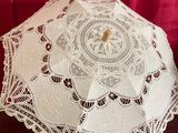 un parapluie en dentelle blanche posé sur une table à côté d'un rideau rouge