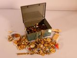 une boîte remplie de bijoux en or posée sur une surface blanche