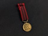 a gold medal with a red ribbon on a black surface