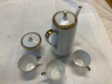 four cups and a teapot sitting on a table