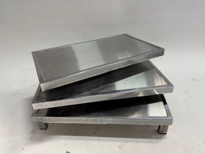 trois plateaux métalliques empilés les uns sur les autres sur une table
