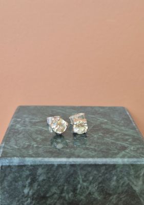 une paire de boucles d'oreilles en diamant posée sur un écrin en marbre vert