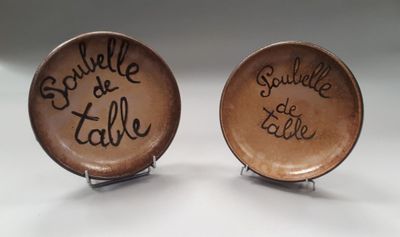 two brown plates with writing on them sitting on a table