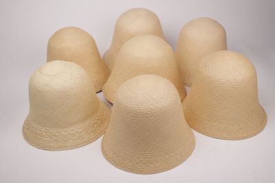 six chapeaux de paille sont alignés sur une surface blanche