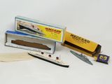 un bateau miniature et une boîte d'allumettes posés sur une surface blanche