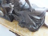 a bronze statue of a woman sitting on a chair