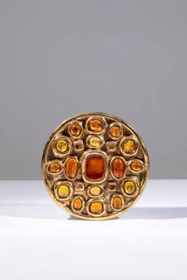 un gros plan sur une bague en or sertie de pierres orange et jaunes