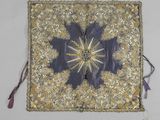 un coussin brodé et orné de perles, décoré d'un motif en forme d'étoile