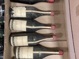 six bottles of wine are in a cardboard box on a table