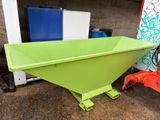 a green dumpster sitting in front of a blue and red truck