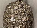 a metal pineapple on a glass shelf on a wall