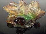 une figurine en verre représentant une feuille et un gland sur un fond noir