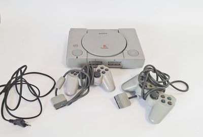 a video game console and two controllers on a white table