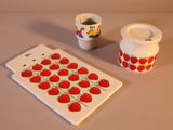 une assiette blanche ornée d'un motif de fraise, posée à côté d'une tasse et d'une soucoupe